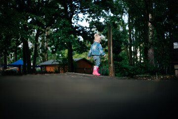 
little cute girl in pink rubber boots on a walk in spring