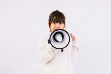 Fototapeta premium Little black haired girl wearing white sweater with bow tie, speaking through a white megaphone.