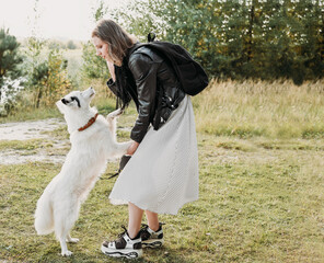 Beautiful young woman with playful young white dog having fun outdoors, full length photo. yakutian laika and her owner. lifestyle, walking in a park leisure