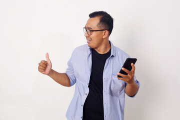 Adult Asian man giving thumb up when holding his mobile phone with happy expression