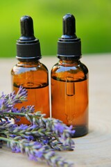Obraz na płótnie Canvas Lavender Essential Oil . Lavender oil and lavender sprigs on blurred green background.
