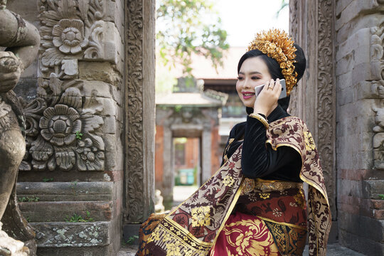 woman wearing traditional Balinese kebaya makes a call