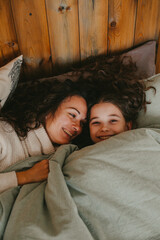 Fototapeta na wymiar Happy young woman with cute teenage daughter posing in bed.