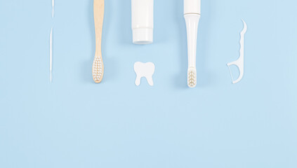 A set of toothbrushes, toothpicks, dental floss and toothpaste on pale blue.