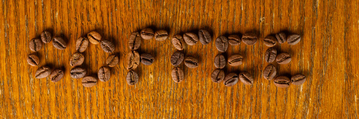 The word coffee is written in grains on the wooden surface - Powered by Adobe