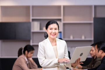 Smart asian woman employee in white suit using laptop for working at workplace