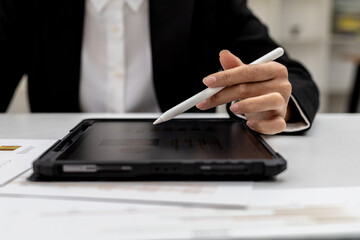 Woman looking at tablet at a screen showing company financial status chart and pressing a calculator to check, a finance worker is checking documents. Concept of company financial management.