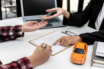 The renter is signing a car rental agreement with the car rental company. After discussing the details and charges with the employee, the employee hand over the car keys to the renter.