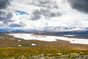 Russia. Magadan Region. A beautiful forest lake against the backdrop of the Big Anngachak mountain range. Autumn in the vicinity of Lake Jack London.