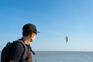 Man photographer  or cameraman to wear 
Hygienic mask or face mask  to take a photo of seagull,Bird photography at Bangpoo, Samut Prakan,Thailand.