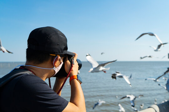 Man photographer  or cameraman to wear 
Hygienic mask or face mask  to take a photo of seagull,Bird photography at Bangpoo, Samut Prakan,Thailand.
