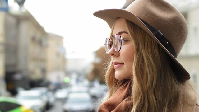 Close-up profile caucasian girl student attractive young woman thinking standing on street in city lady pensively looking into distance outdoors side view millennial blond female with hat and glasses