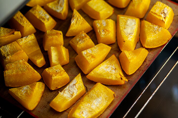 Pumpkin slices baked on a baking sheet in the oven. Homemade food, Vegan food, Healthy food, orange vegetables on a baking sheet and napkin, baked rustic vegetables, pop art, dessert during a diet