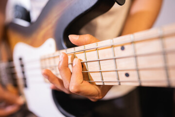 close up of a bassist's hand with tapping technique playing electric guitar bass