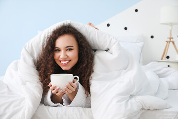 Morning of young woman drinking tea in bed
