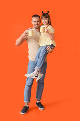 Fototapeta premium Happy daughter and father with cups of hot cocoa on color background