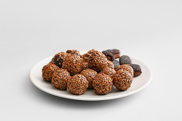 Plate with tasty flax seed candies on light background