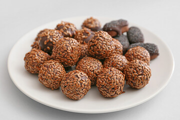 Plate with tasty flax seed candies on light background