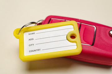 Yellow plastic tag with car key on beige background