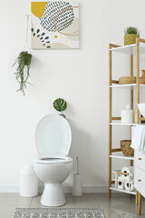 Interior of white restroom with toilet bowl and shelving unit
