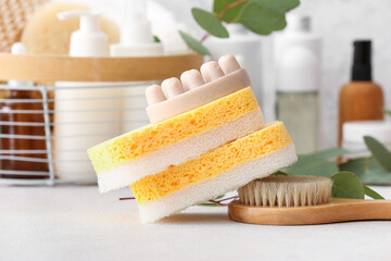 Bath sponges, massage brush and soap bar on light table, closeup