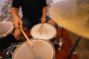 close up of a drummer with drumsticks beating tom-toms and snare drums