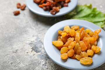 Plate with tasty raisins on grey background, closeup