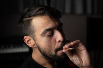 biracial hipster smoking weed  with splif in hand  with a trendy haircut 