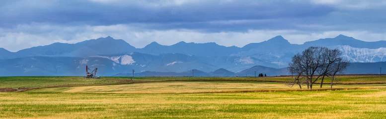 Foto op Plexiglas Canadian Rocky Mountain range beautiful rural Alberta prairies and grassland panoramic landscape. Oil pump jack in farmland © Jordan Feeg