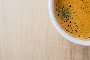Close up photo of fresh espresso with foam in white cup, top view from above