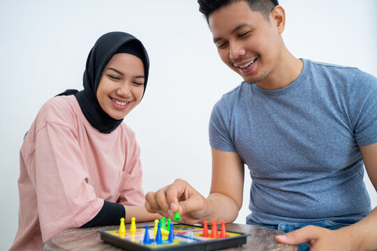 Man and woman in headscarf playing ludo using a board