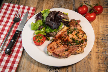 Recipe for grilled pork chop, maple syrup and fresh cilantro marinade, parsley, garlic, served with a salad.