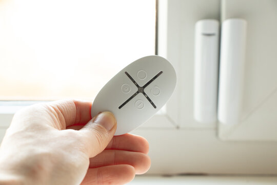 home security system on the windows, an opening sensor and a remote control in the hands of opening and closing, a remote control from the house alarm