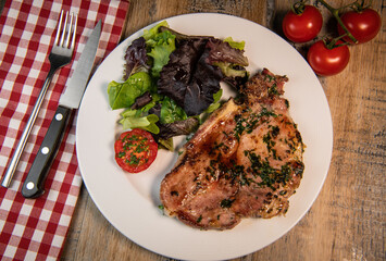 Recipe for grilled pork chop, maple syrup and fresh cilantro marinade, parsley, garlic, served with a salad.