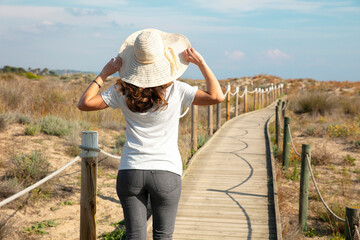 woman tourist walking on wooden path across the dunes
