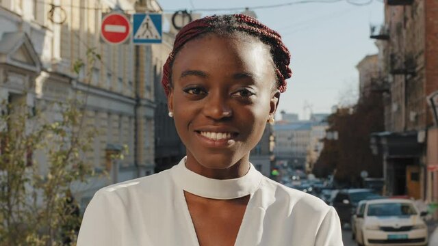 Portrait of beautiful happy african american business woman exited student girl posing in city street. Close up female toothy smiling with white smile lady looking at camera dental client outdoors