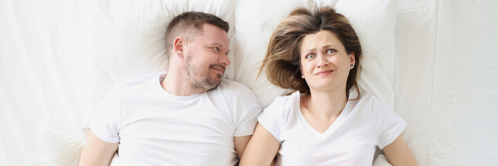 Frustrated woman lies on bed with smiling man closeup