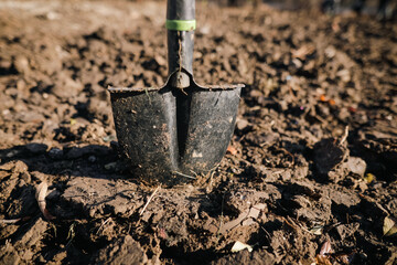 Shallow depth of field (selective focus) image with a metal shovel on a piece of agricultural plowed land.