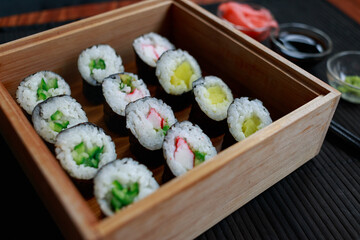 Sushi rolls with vegetable filling over dark bamboo background
