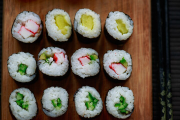 Sushi rolls with vegetable filling over dark bamboo background