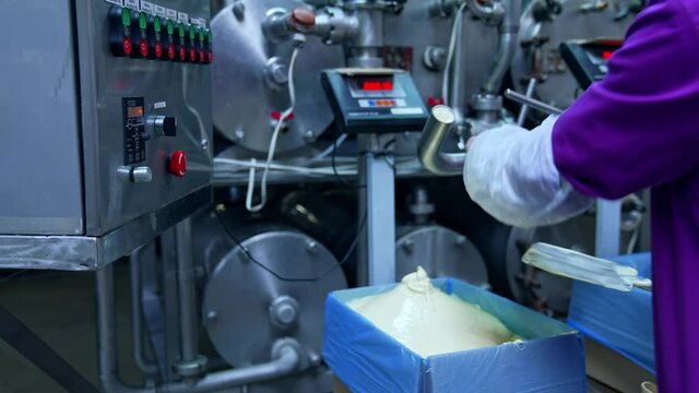 Liquid butter is pouring from the pipe into the container. Factory for the production of butter. Automated line. Food production