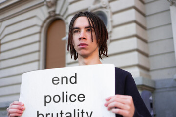 A male student is protesting against police brutality in front of the courthouse.
