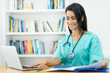 Laughing mexican female nurse at desk at work