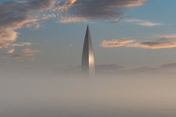 The top of the skyscraper sticks out of the morning fog