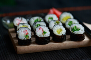 Sushi rolls with vegetable filling over dark bamboo background