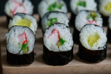 Sushi rolls with vegetable filling over dark bamboo background