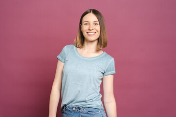 Portrait of smiling woman standing folded hands wearing casual blue tshirt isolated on pink background with copy sace