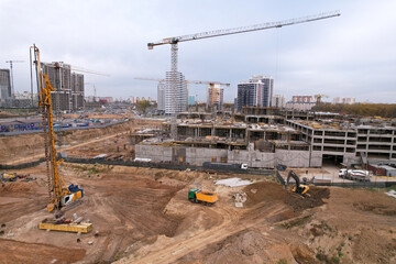 Drilling rig and Pile driver at construction site. Deep foundation machine. Foundations construction work. Ground drilling and Piling. Excavator load the sand into dump truck. Tower crane on formwork.
