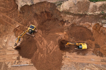 Excavator dig ground for sewerge construction. Trench for laying a concrete well ring and sewer pipe. Sewage drainage and concrete pipes. Earth-moving heavy equipment. Earthworks at construction site.