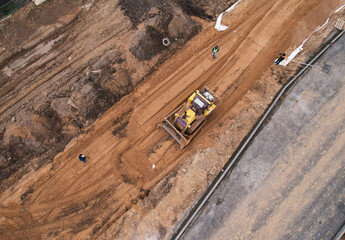 Dozer levels the ground during road construction, aerial view. Compaction of soil for laying...